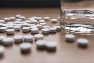 Buprenorphine pills lay on table next to glass of water